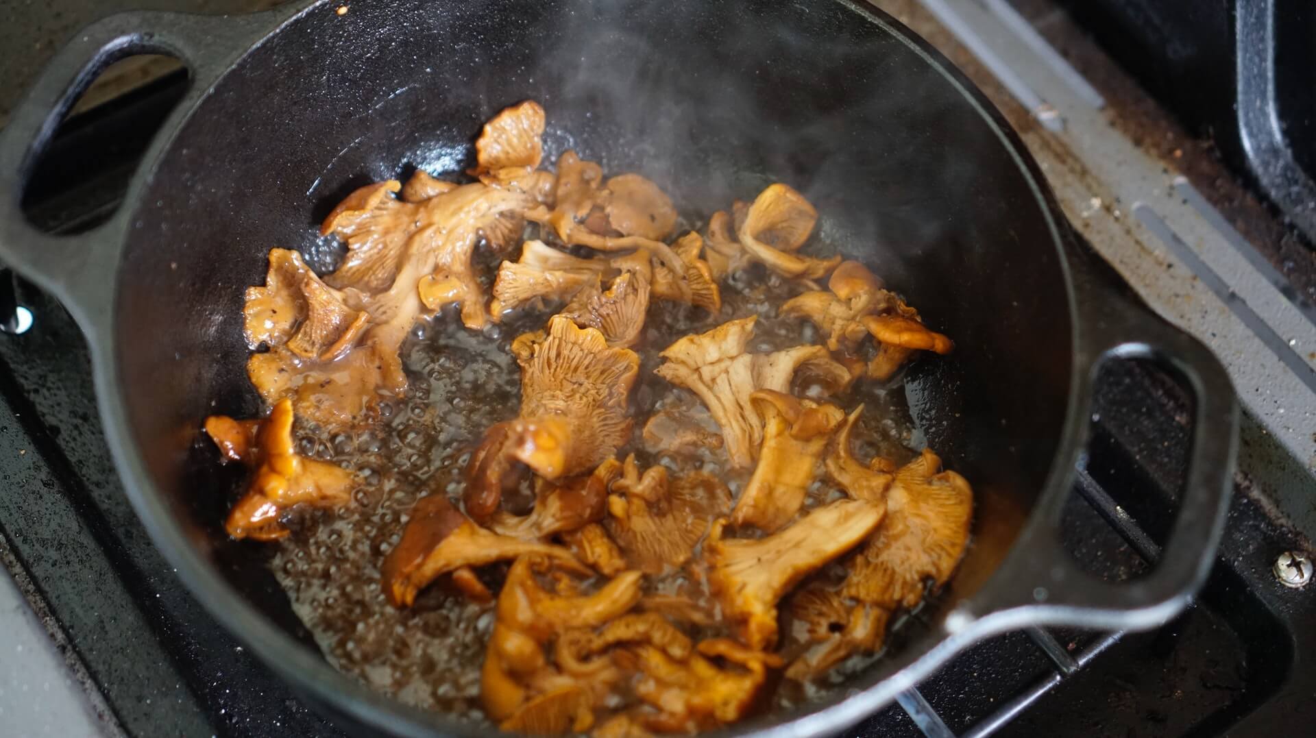 A hot pan full of oil and golden chanterelle mushrooms.