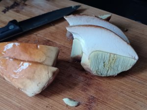 slice brown mushrooms with white centers and yellow gills on wooden table